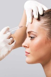 Side view of a young woman receiving botox injection.