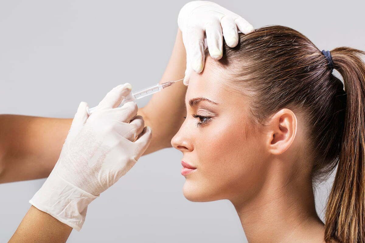 Side view of a young woman receiving botox injection.